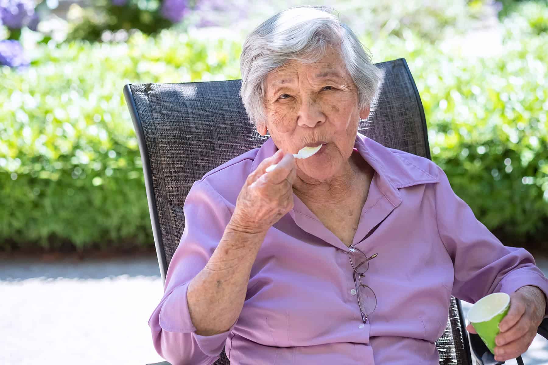 Elderly Woman Enjoying Ice Cream In The Sun